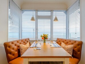 A dining area with a wooden table, two brown leather booths, white blinds, and pendant lights. - 1 Bed in Hythe (oc-89970) (Hythe)