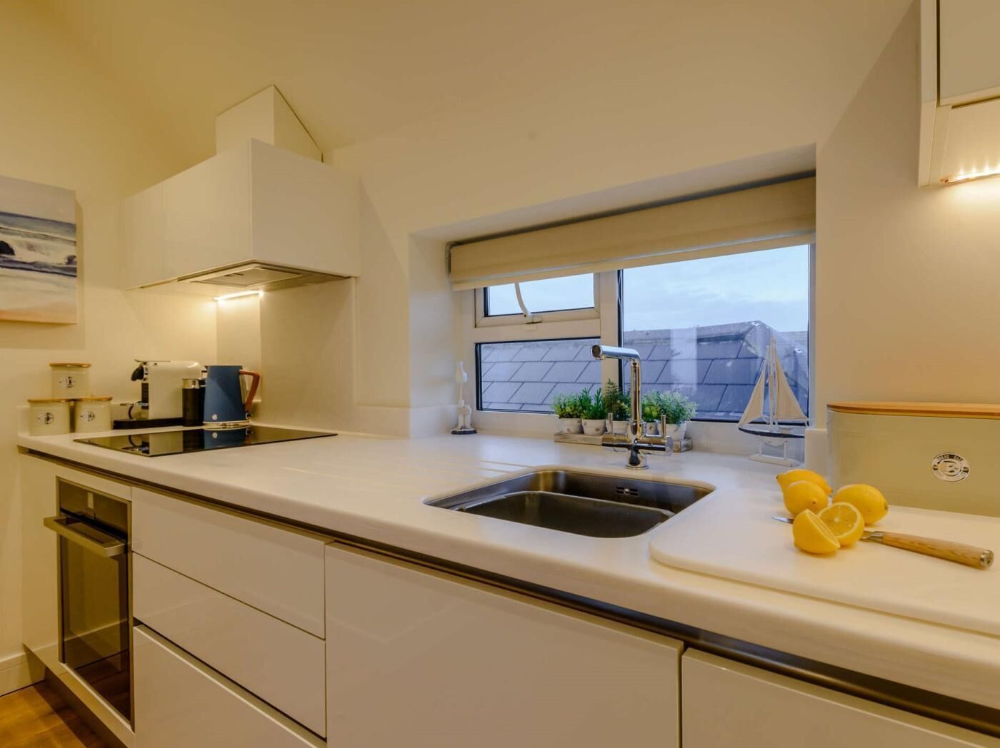 A modern kitchen with a large window, a double sink, and a countertop with kitchen appliances.