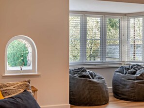 Ein Zimmer mit einem großen Fenster, einem kleinen Rundbogenfenster und zwei Sitzsäcken.