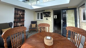 A room with a skylight, a dining table with chairs, a bookshelf, and a stone wall. - 2 Bed in Brecon (oc-51153) (Llandefalle)