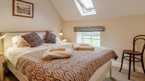 A bedroom with a bed, a nightstand, a chair, a window with a view, and a skylight. - 2 Bed in Brecon (oc-51153) (Llandefalle)