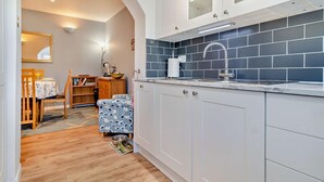 Una cucina con mobili bianchi, uno schienale blu in piastrelle e un tavolo da pranzo in legno con sedie.