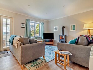 A living room with two sofas, a TV, a fireplace, and a window with curtains. - 3 Bed in Great Yarmouth (oc-93210) (Winterton-on-Sea)