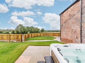 A backyard with a hot tub, a brick wall, and a wooden fence.