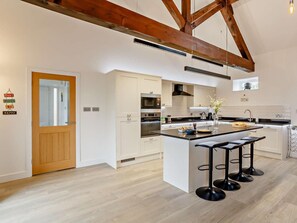 Een moderne keuken met een centraal eiland, barstoelen en een houten plafond.