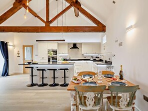 A modern kitchen with a central island, bar stools, and a dining table set for four.