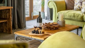 Una mesa de centro de madera con una botella de vino, una copa y un plato de bayas y galletas.