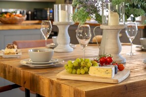 A wooden table with a cheese platter, grapes, and tomatoes, surrounded by wine glasses and a bowl. - 1 Bed in Richmond (oc-93264) (Hudswell)
