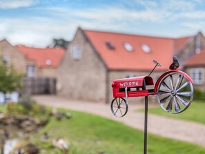 A mailbox with a bicycle and a bird on it, set against a backdrop of houses with red roofs. - 1 Bed in Richmond (oc-93264) (Hudswell)