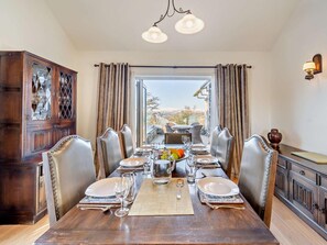 A dining area with a wooden table set for six, surrounded by upholstered chairs. - 5 Bed in Windermere (oc-93302) (Troutbeck Bridge)