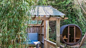 Un pontile in legno con una struttura a tetto in vetro, una cupola circolare in legno e un divano blu.