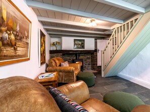 Ein gemütliches Wohnzimmer mit Kamin, Ledermöbeln und einer Treppe.