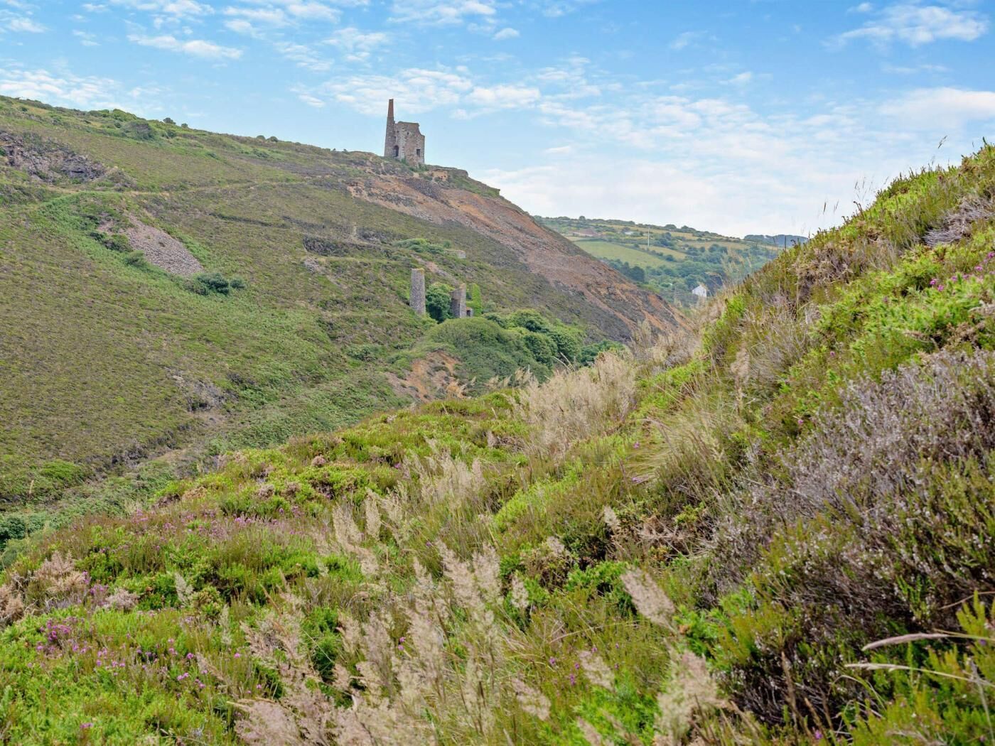 Eine hügelige Landschaft mit einem historischen Steinbau.