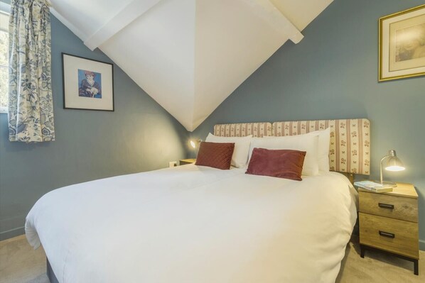 A bedroom with a bed, a nightstand, a lamp, and a framed picture on the wall.