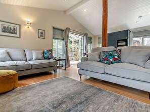 A modern living room with two grey sofas, a wooden floor, and a large window. - 2 Bed in Truro (oc-93310) (Porthtowan)