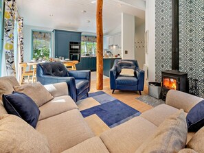 A living room with a sofa, two armchairs, a fireplace, and a kitchen in the background. - 3 Bed in Truro (oc-93312) (Porthtowan)