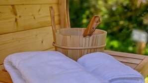 A wooden sauna bench with a towel and a wooden bucket with a handle.