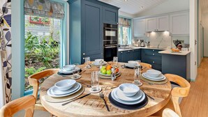 A dining area with a round wooden table set for four, surrounded by wooden chairs.