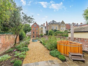 A garden pathway leading to a wooden hot tub with steps, surrounded by a brick wall and various plants. - 6 Bed in Ludlow (oc-93327) (Ludlow)