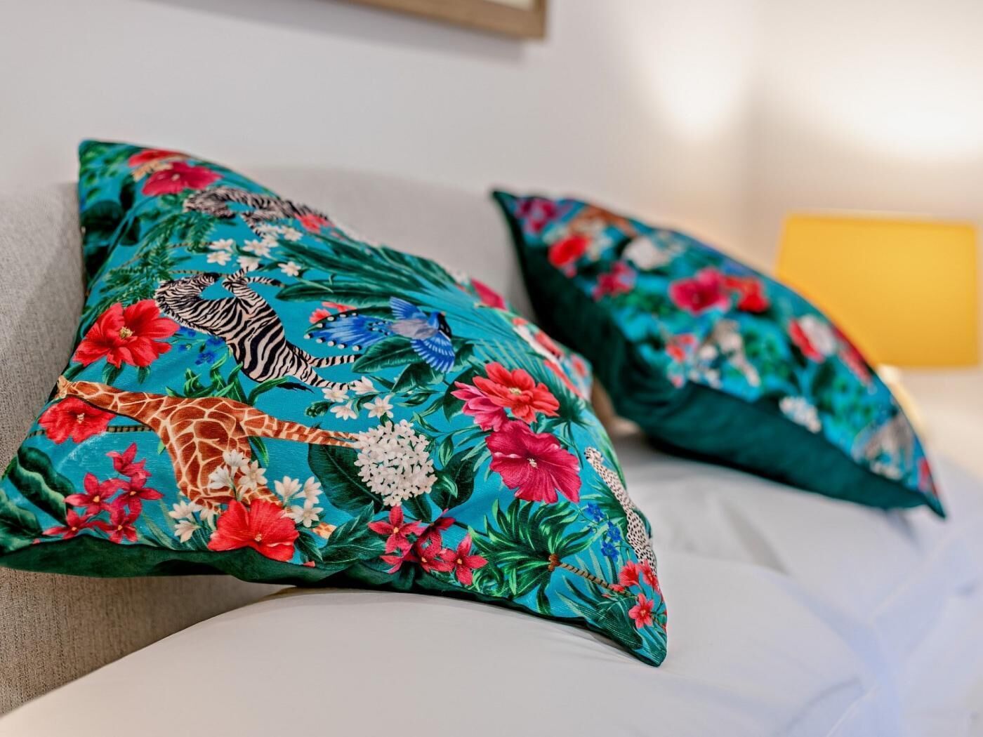 Kussens met tropische bloemenprints op een bed.
