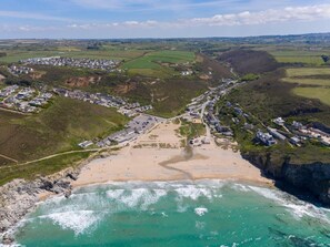 An aerial view of a coastal town with a beach, residential areas, and agricultural fields.
