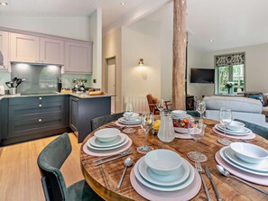 A modern kitchen with a central island, dining table set with plates, glasses, and cutlery.