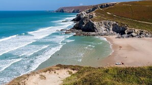 Eine Küstenlandschaft mit Sandstrand, Felsen und dem Meer.