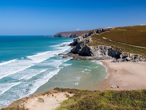 Eine Küstenlandschaft mit Sandstrand, Felsen und dem Meer.