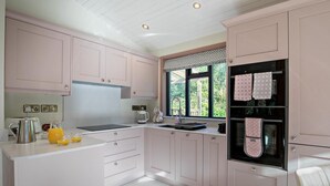 Eine moderne Küche mit rosa Schränken, einem Edelstahl-Kühlschrank und einem Fenster mit Blick auf Grünflächen.