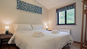 Ein Schlafzimmer mit einem Bett, zwei Nachttischen, einem Fenster mit Blick und einem Wandbild.