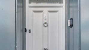 Uma porta branca com a inscrição 'THE HIVE' acima, um toque e uma fechadura.