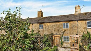 A stone house with a garden, a wooden gate, and a small wooden structure. - 1 Bed in Chipping Campden (oc-93393) (Chipping Campden)