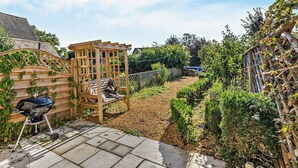 A garden with a wooden pergola, a barbecue grill, and a paved patio area. - 1 Bed in Chipping Campden (oc-93393) (Chipping Campden)