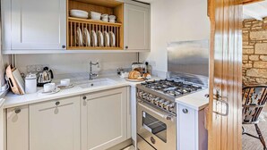 A kitchen with a built-in oven, a gas stove, and a wooden shelf above the sink. - 1 Bed in Chipping Campden (oc-93393) (Chipping Campden)