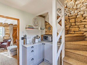 A compact kitchen with a white countertop, a clock, and a stone wall. - 1 Bed in Chipping Campden (oc-93393) (Chipping Campden)