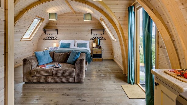 Una habitación acogedora con cama, sofá, comedor y ventana con cortinas.