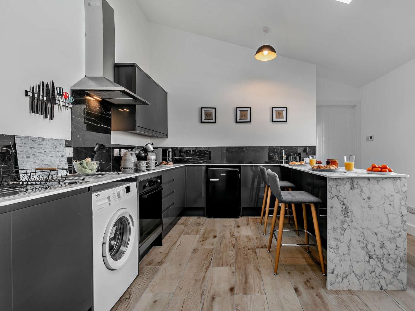 Une cuisine moderne dotée d’un lave-linge intégré, d’un îlot central avec des tabourets de bar et d’un coin repas.