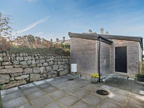 A stone wall, a small wooden structure, and a paved area with a manhole cover. - 1 Bed in Penzance (oc-93410) (Sennen)