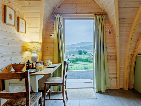 A wooden interior with a dining table, chairs, and a view of the outdoors.