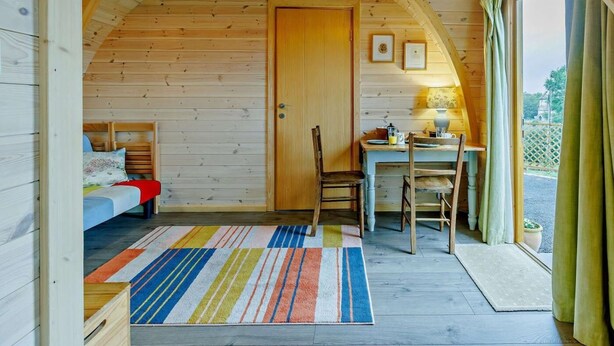 Ein gemütliches Blockhaus-Interieur mit einem Bett, einem Esstisch und einem Fenster.