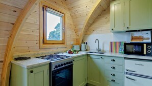 Eine Küche mit Holzwänden, einem Gasherd, einem Backofen, einer Spüle und einer Mikrowelle.