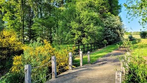 A wooden boardwalk through a lush green landscape with a fence on one side. - 3 Bed in King's Lynn (oc-93412) (Middleton)