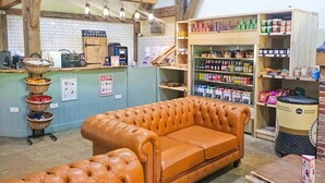 A cozy interior with a leather sofa, a coffee station, and shelves stocked with snacks and beverages. - 3 Bed in King's Lynn (oc-93412) (Middleton)