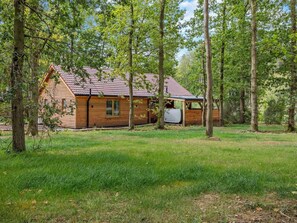 A wooden cabin with a red-tiled roof, surrounded by trees and grass. - 3 Bed in King's Lynn (oc-93412) (Middleton)