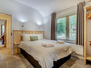 A bedroom with a wooden headboard, a large window with curtains, and a radiator. - 3 Bed in King's Lynn (oc-93412) (Middleton)