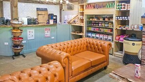 Een gezellig interieur met een leren bank, een koffiehoek en planken vol diverse producten.