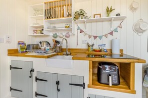 Eine kompakte Küche mit Spüle, Holz Arbeitsplatte und integriertem Kaffeeautomaten.