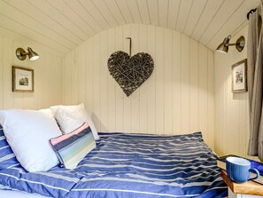 Ein Schlafzimmer mit einem Bett, Kissen, einer herzförmigen Wanddekoration und Wandlampen.