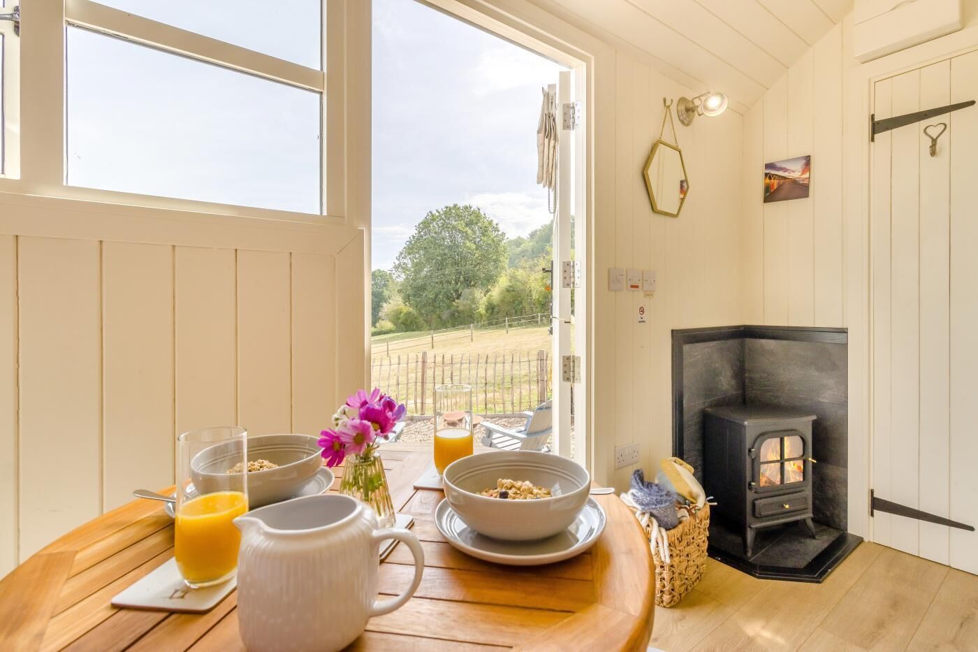 A cozy room with a wooden table set for breakfast, a fireplace, and a view of the outdoors.