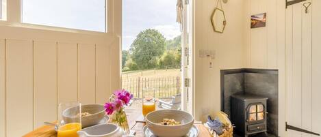 A cozy room with a wooden table set for breakfast, a fireplace, and a view of the outdoors.